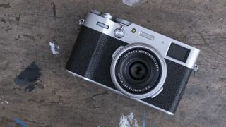 Beste kompaktkamera, her representert ved mini-kameraet Fujifilm X100V som ligger på en treplate.