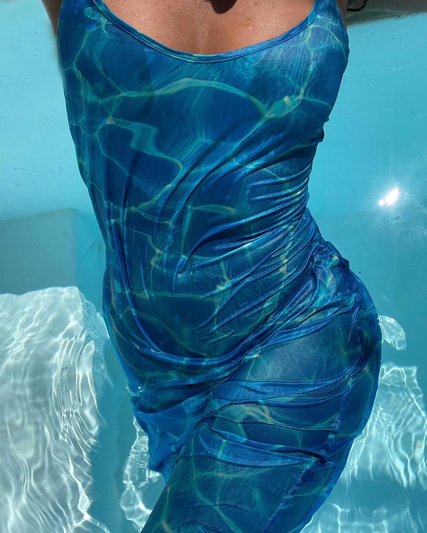 An image of a dress with water patterns on it emerging out the water.