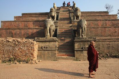 In this photo taken on Tuesday, March 1, 2016, a Buddhist monk stand in front of the destroyed temple from last year earthquake in Bhaktapur Durbar Square, near Katmandu, Nepal. 