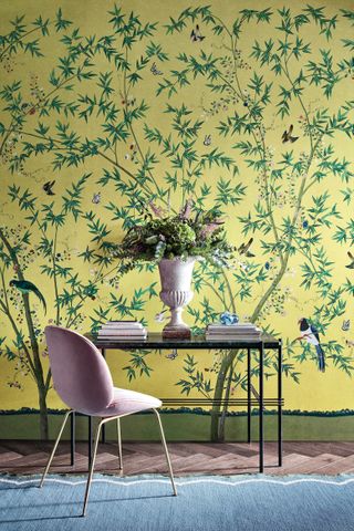 console table with pink chair, blue rug and yellow wall mural floral bird wallpaper