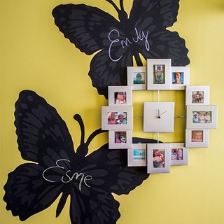 yellow wall with black butterfly stickers and photo frame clock