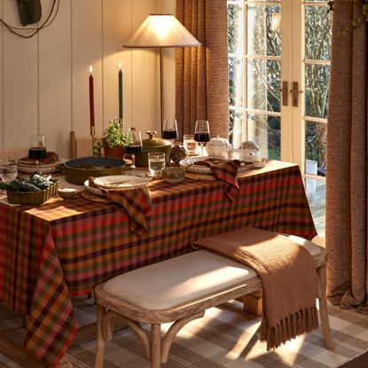 A set dining table with an autumn theme dressed with a multicoloured gingham tablecloth and matching napkins
