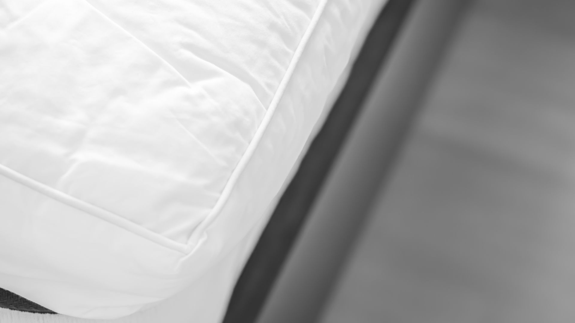 Image shows the corner of a mattress topper placed on a grey mattress