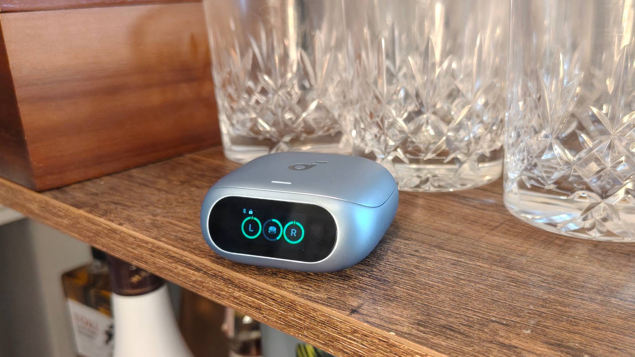 The Anker Soundcore Liberty 5 Pro on a shelf, next to some glasses.