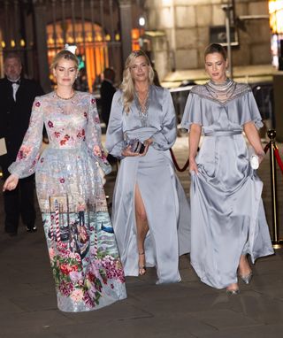 Kitty, Amelia and Eliza Spencer wearing blue evening gowns walking outside at night