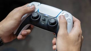 A PlayStation 5 DualSense controller being held by two hands