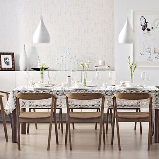 dining area with white wall and dinner table with tablecloth and chairs