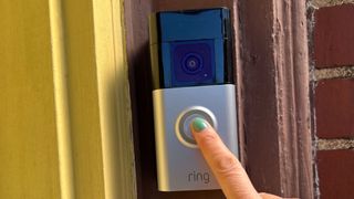 A finger presses the button on a Ring Battery Doorbell Plus