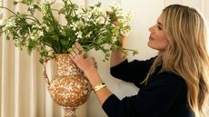 designer shea mcgee styled a bunch of small white flowers in a terracotta splattered vase for her collaboration with sharland england