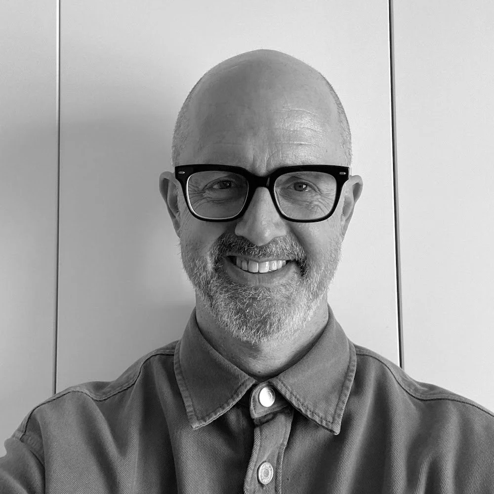 male with shaved head, beard, glasses wearing shirt