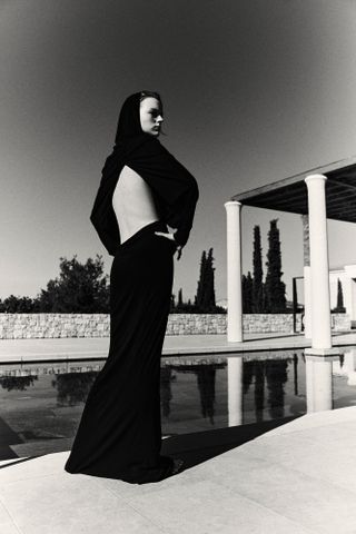 Woman in open back black dress by pool in Greece