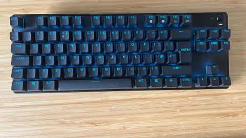 SteelSeries Apex Pro TKL Wireless gaming keyboard on a wooden desk without wrist rest