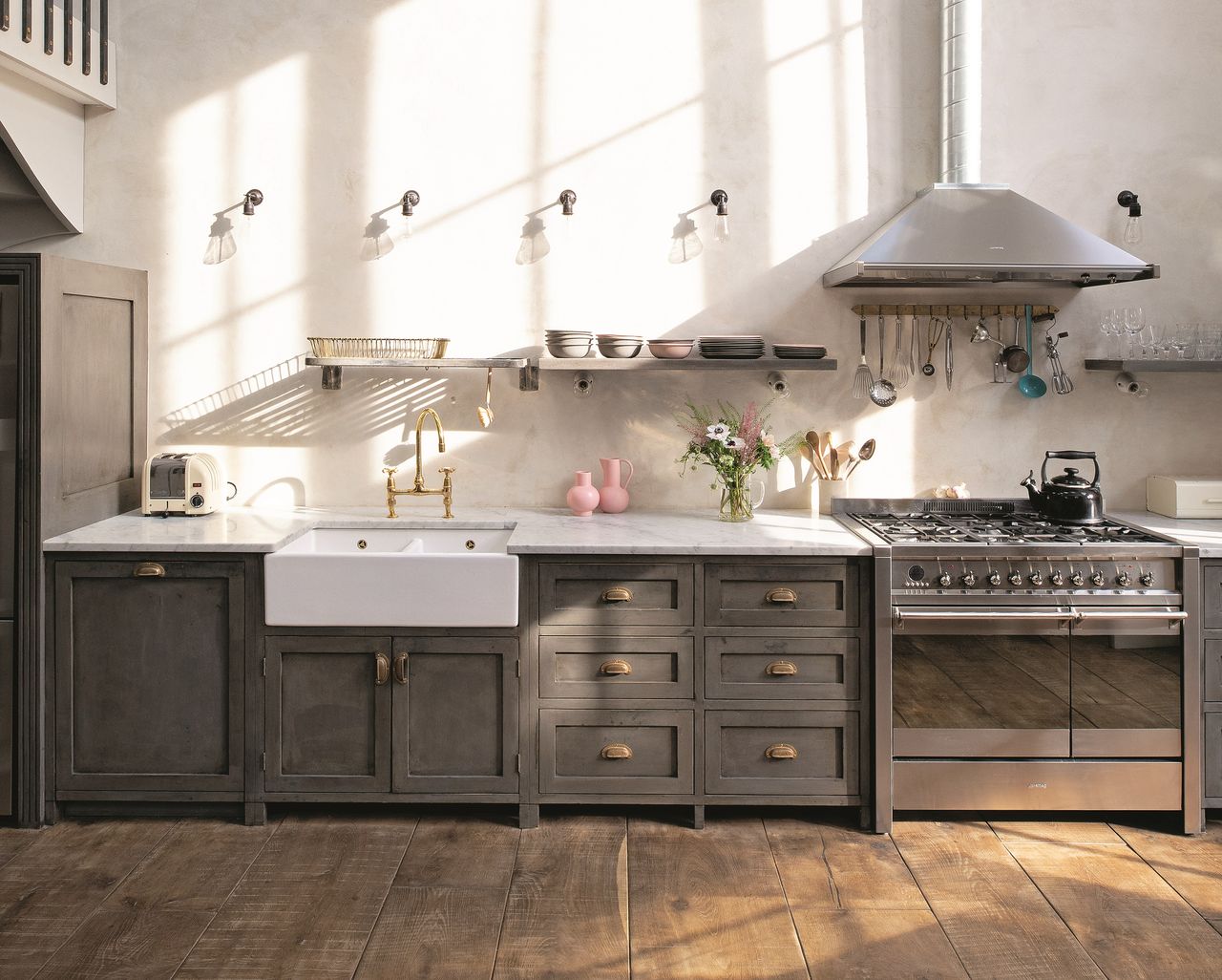 A kitchen with a butler sink, grey cabinetry, and stainless steel appliances