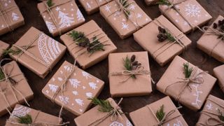 A selection of small boxed Christmas presents wrapped in Kraft paper decorated with white designs