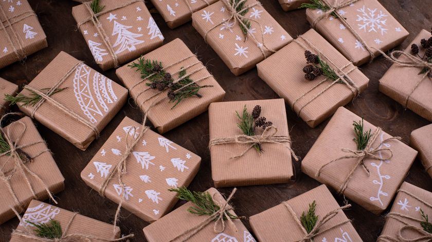 A selection of small boxed Christmas presents wrapped in Kraft paper decorated with white designs 