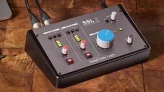 An SSL 2 audio interface on a wooden desk with a laptop