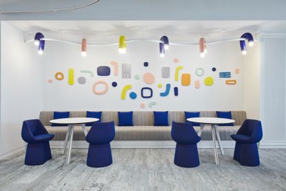 Office space in Abu Dhabi featuring colourful shapes on the wall, yellow, pink and blue lamps and bright blue seating in a banquet area