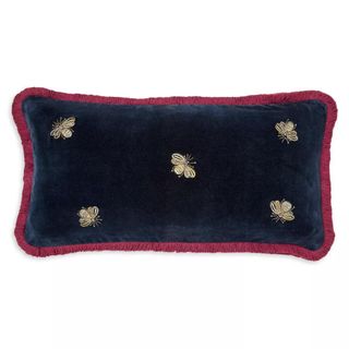 A dark blue and red pillow with bees embroidered on