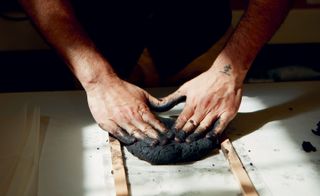 Black pulp being kneaded by hands