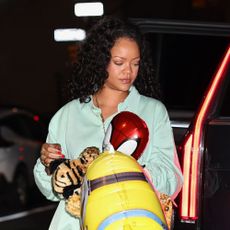 Rihanna wearing a teal polo longsleeve shirt, balloon pants, and snakeskin sandals