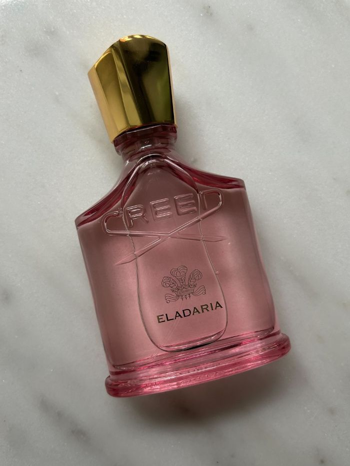 A picture of a Creed perfume on a marble background