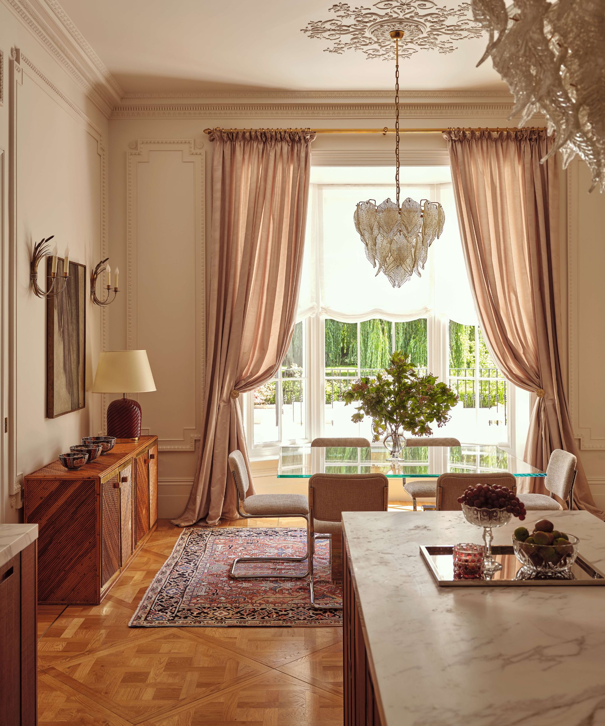 a pale pink painted victorian apartment with a dining area with mid century furniture