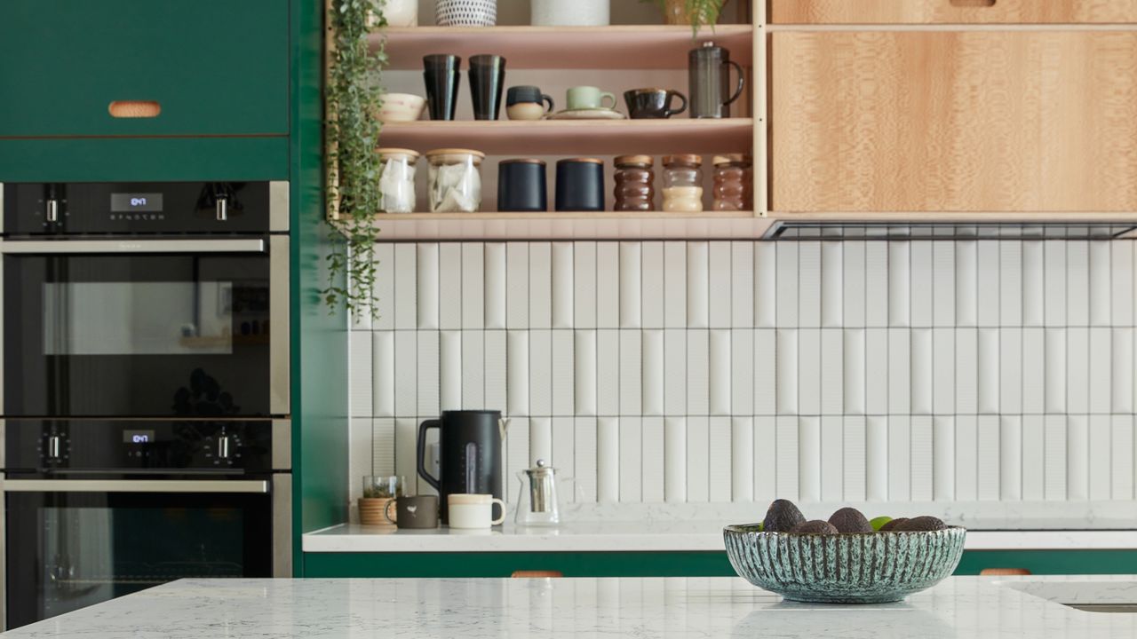 Green kitchen with white metro tiles stacked along wall.