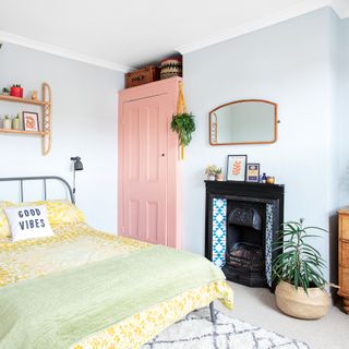 Bedroom with pink built in wardrobe, tiles fireplace and yellow bedding