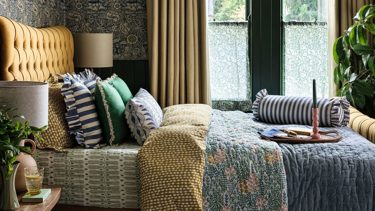 Bedroom with mustard yellow upholstered bed dressed with stripes and patterns
