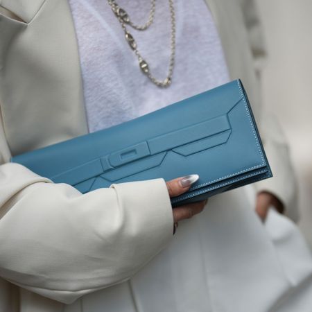 Woman wearing cat eye nails holding a Hermes clutch bag 