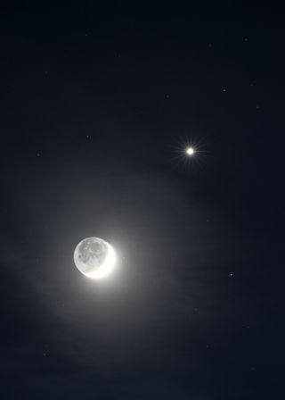 a thin crescent moon beside a pale yellow orb