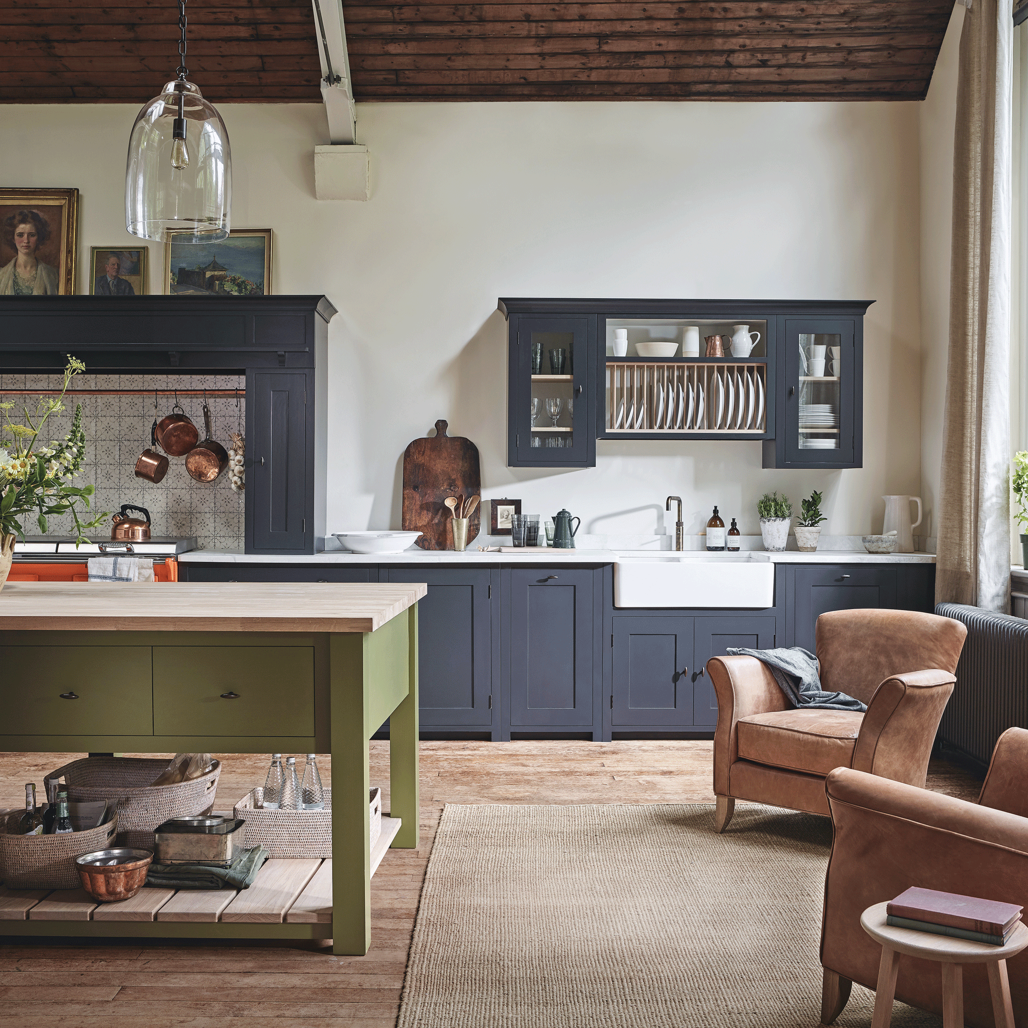 Blue kitchen with green island and separate seating area with two chairs and a rug