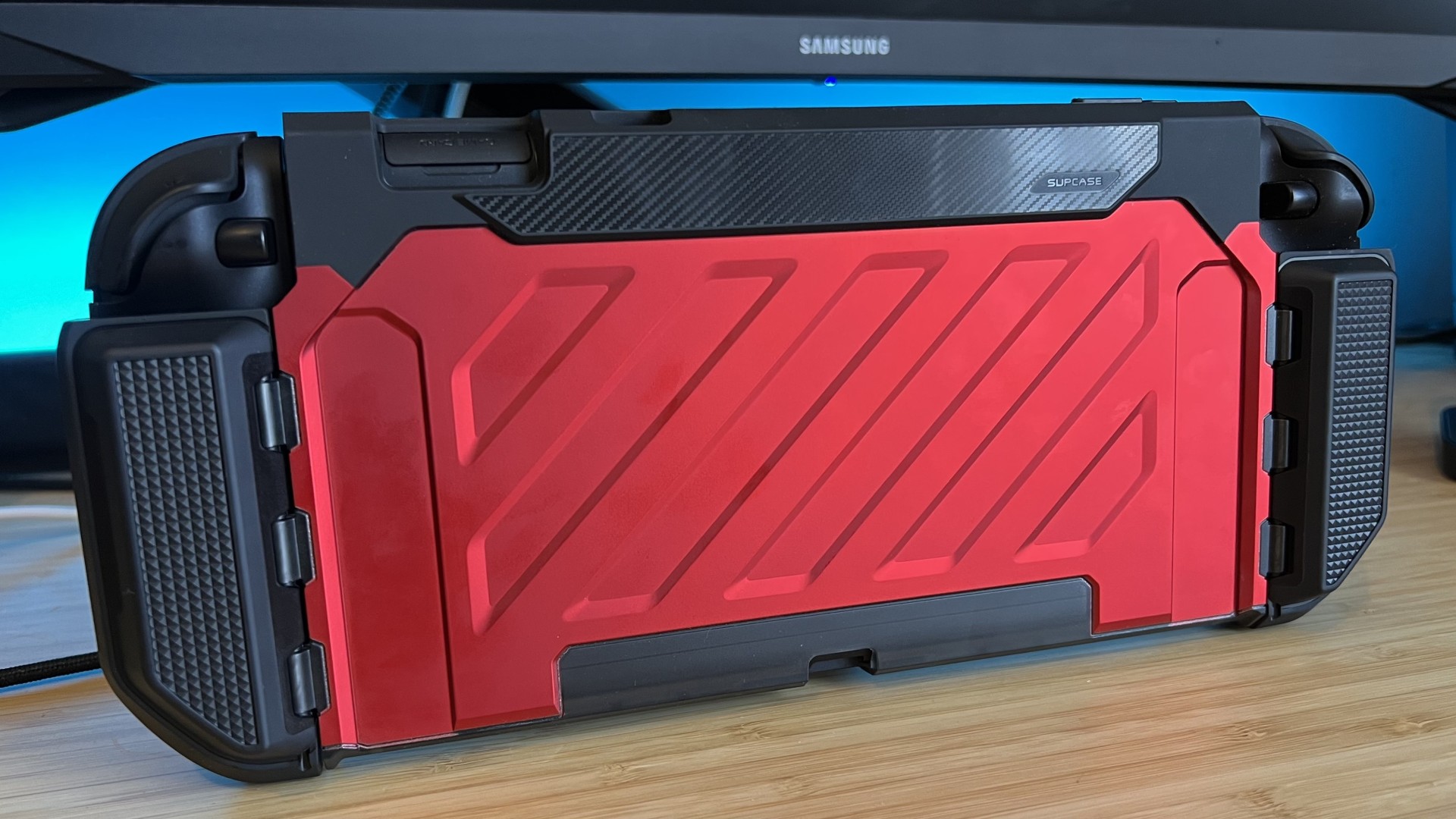 SupCase Unicorn Beetle Pro Nintendo Switch 2 shell case in red attached to a handheld and standing up on a wooden desk