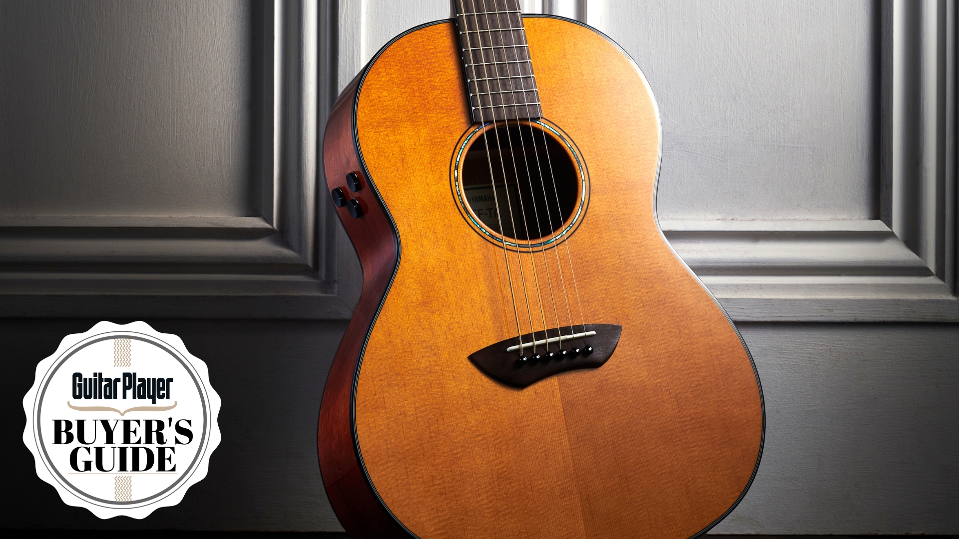 A Yamaha TransAcoustic acoustic guitar leaning against a white wall