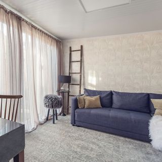 Interior of Green Retreats garden room lounge with navy blue sofa and decorative wooden ladder