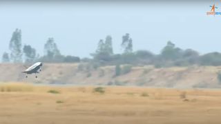 a small space plane comes in for a landing with brown hills in the background