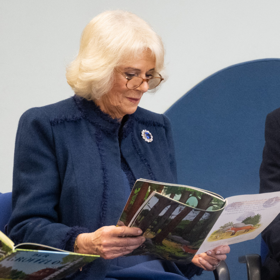 Queen Camilla wearing a blue coat reading a book