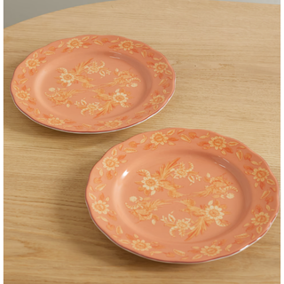 two orange dinner plates with yellow painted pattern