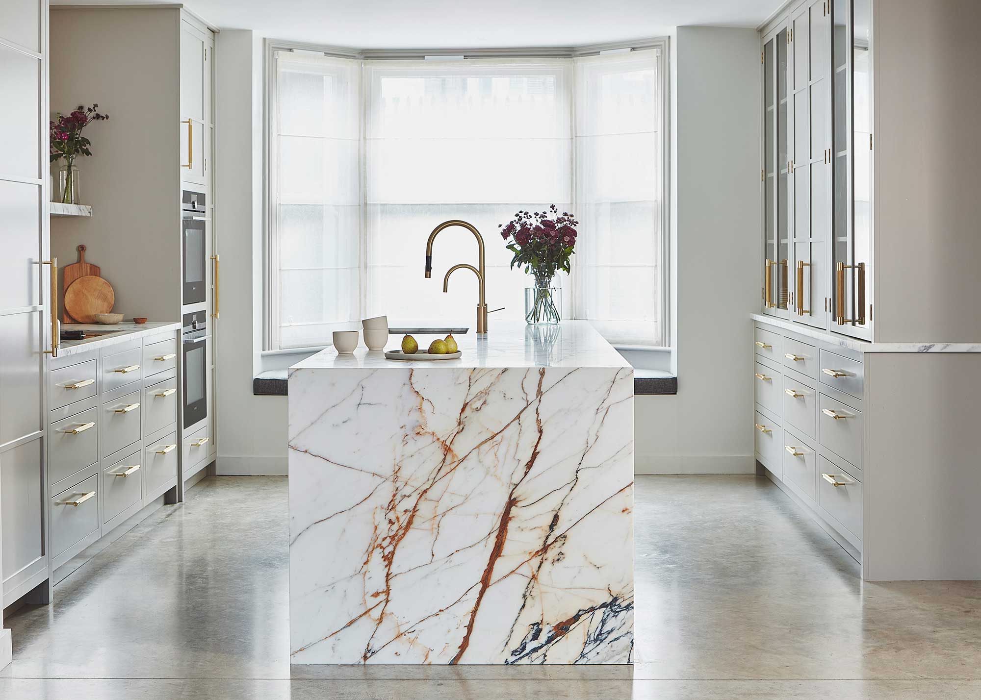 white kitchen with marble kitchen island and brass kitchen tap
