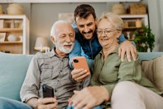 A young man shows off digital assets to an old couple who are seated on a sofa (image: Getty Images)