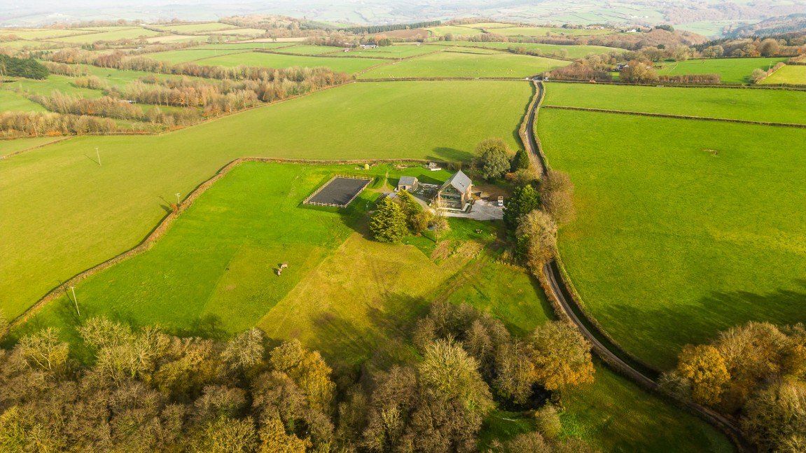 An aerial view of the home with bat palace seen as well as the American style stables and surrounding landscape