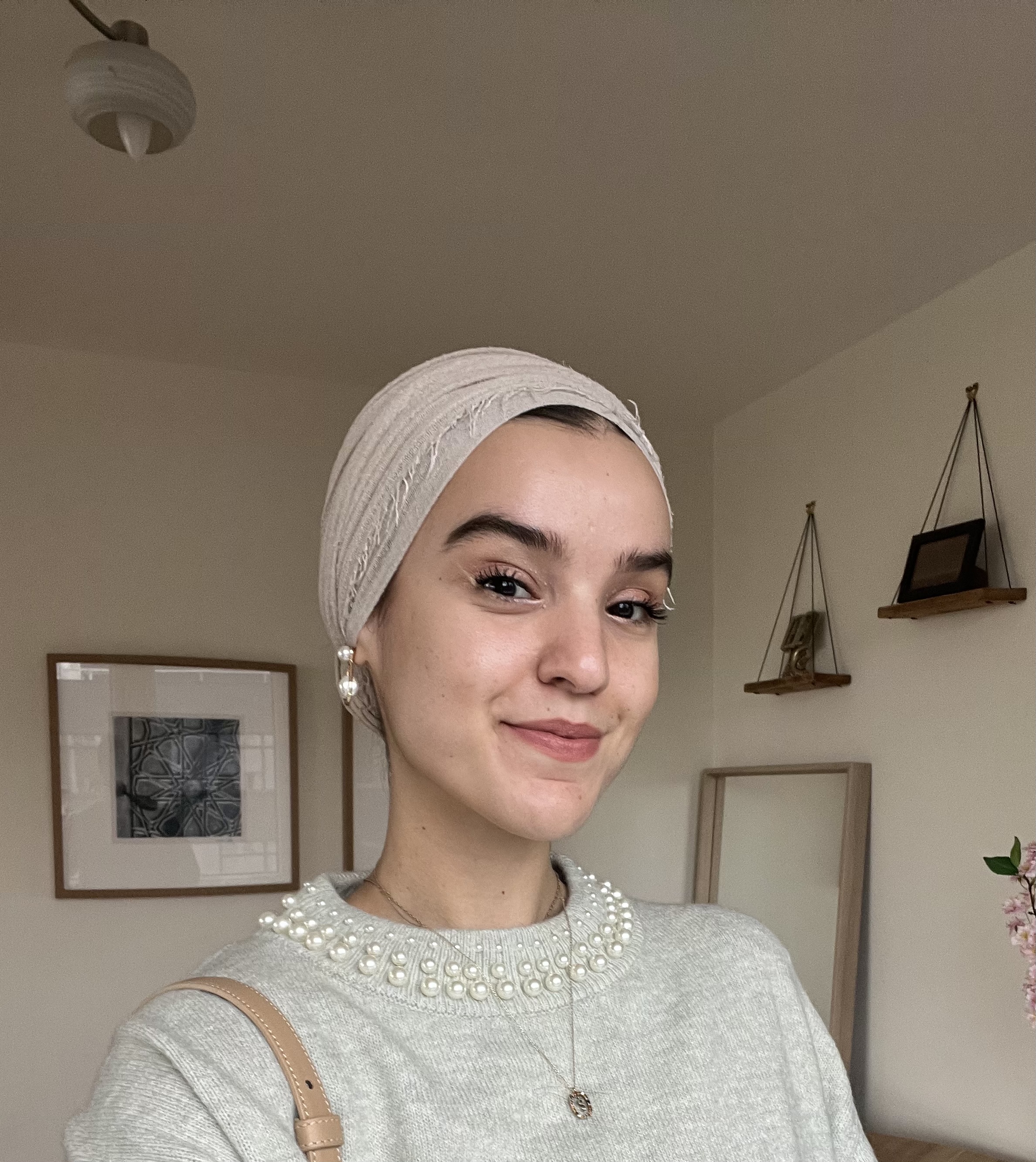 A headshot of a woman wearing a headscarf smiling at the camera