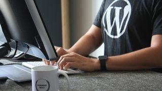 man wearing a WordPress shirt working on a computer