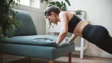 Woman doing push-up at home with her hands on the edge of a couch