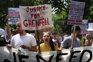 LONDON, ENGLAND - JUNE 21:Protesters hold signs calling for justice for the victims of the Grenfell Disaster and shout slogans as they march towards Westminster during an anti-government prot
