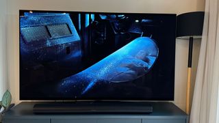 Film scene from Aliens shown on the LG G4 OLED TV. A floor lamp emitting blue light is to the right of the TV.