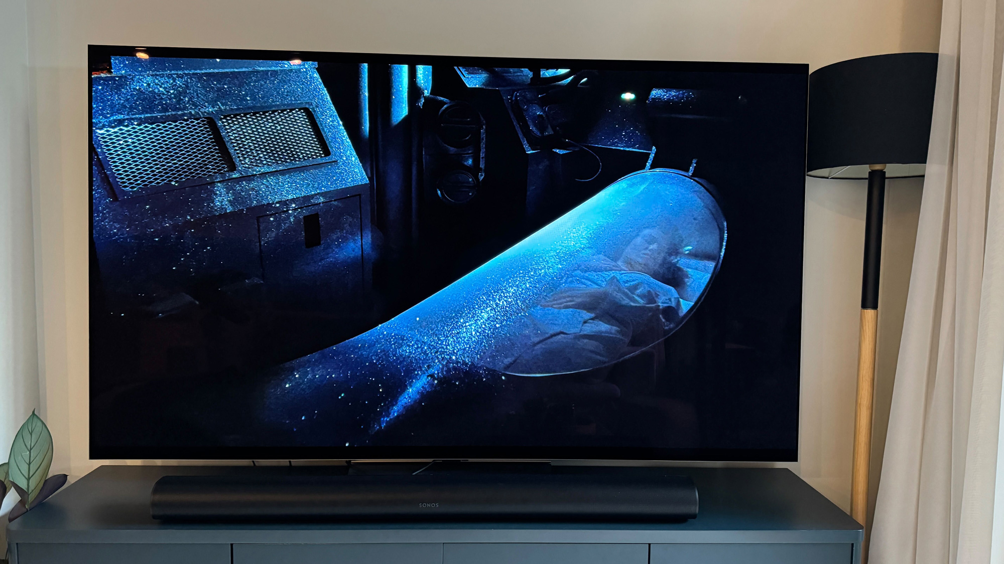 Film scene from Aliens shown on the LG G4 OLED TV. A floor lamp emitting blue light is to the right of the TV.