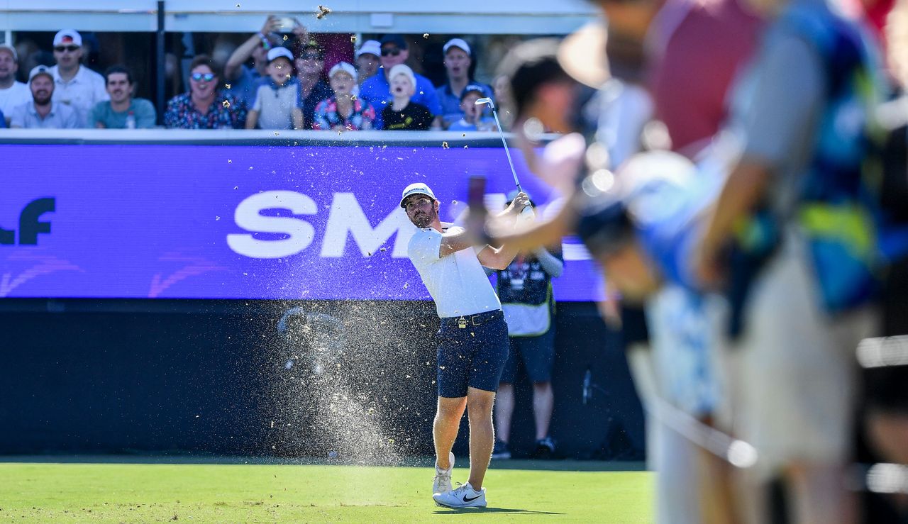 Matt Wolff strikes his shot in front of a Smash GC board