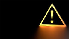 Ransomware concept image showing a yellow-colored alert symbol pictured against a jet black background.