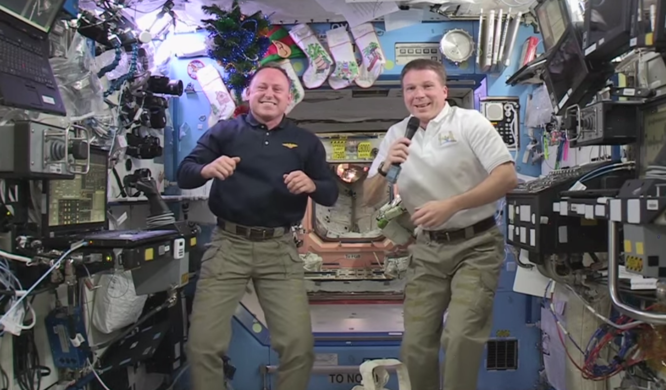 NASA astronaut Barry &quot;Butch&quot; Wilmore (left) floats with ESA astronaut Samantha Cristoforetti (center) and NASA&#039;s Terry Virts (right) record a New Year&#039;s greeting on the International Space Station for people on Earth.